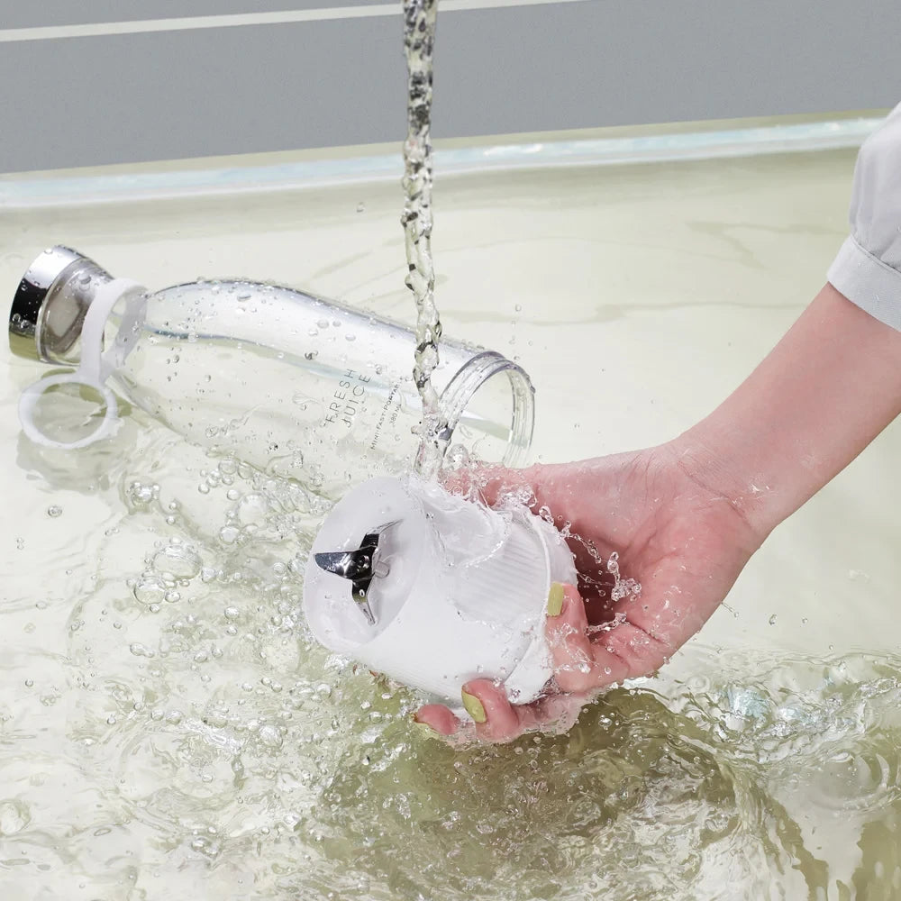 Person holding a portable blender under running water from a faucet