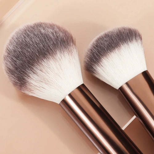 Two makeup brushes with brown handles on a beige background