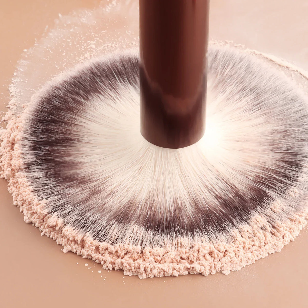 Makeup brush with pink bristle head and brown handle on a beige background